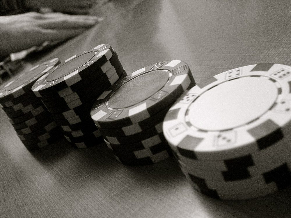 Cuatro torres de fichas de poker de altura decreciente sobre una mesa