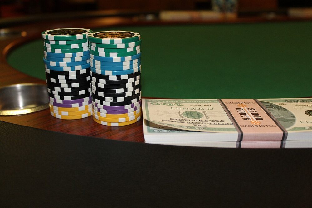 Torres de fichas y fajos de billetes sobre el tapete verde de una mesa de cash game