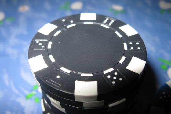 Primer plano de una ficha de poker negra sobre un fondo azul