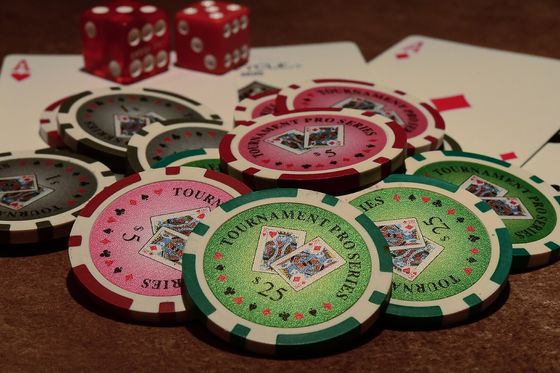 Fichas de torneo de varias denominaciones esparcidas junto a cartas y dados