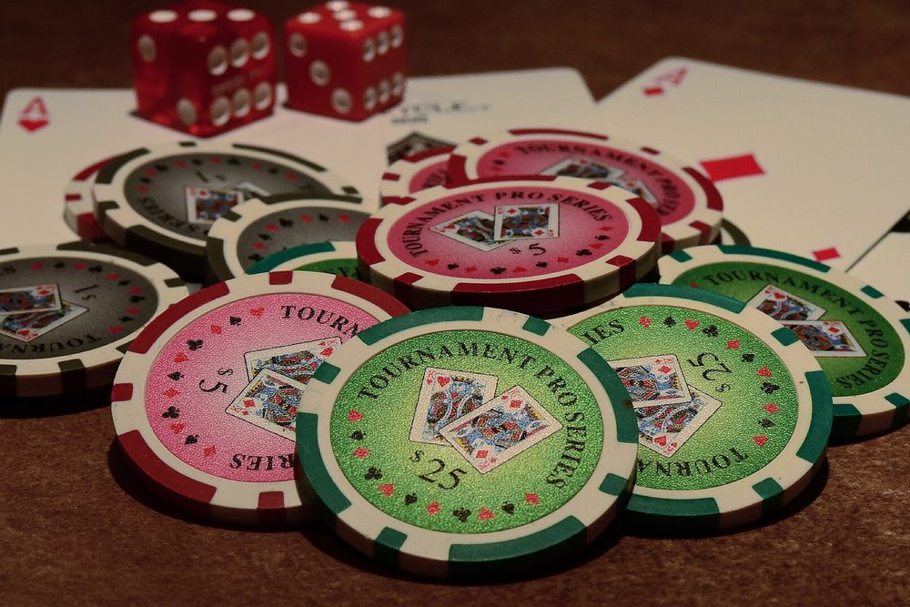 Fichas de torneo de varias denominaciones esparcidas junto a cartas y dados