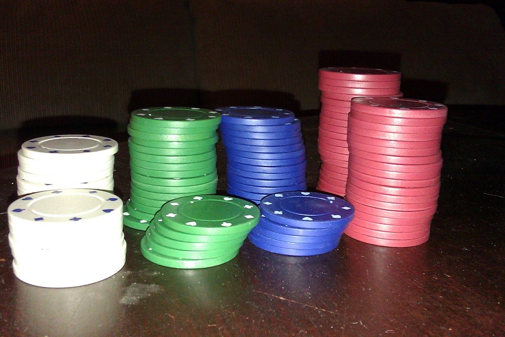 Torres de fichas de poker verdes, blancas y rojas sobre una superficie clara