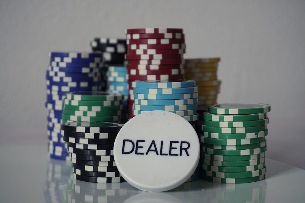 Un botón de dealer blanco delante de torres de fichas de poker