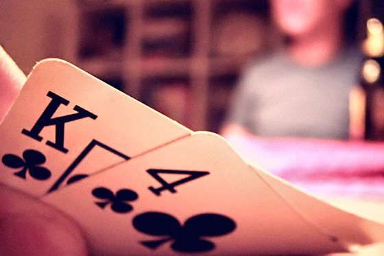 Un jugador levantando la esquina de un rey y un cuatro como cartas propias