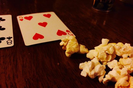 Dos cartas y palomitas esparcidas sobre una mesa de madera en una partida casera