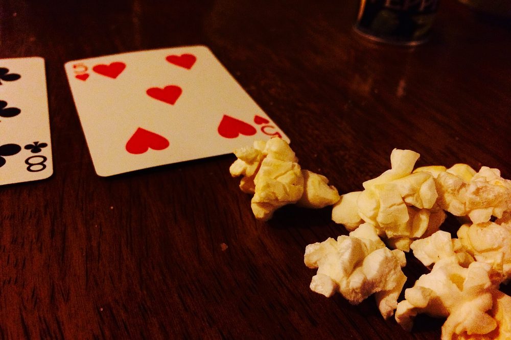 Dos cartas y palomitas esparcidas sobre una mesa de madera en una partida casera