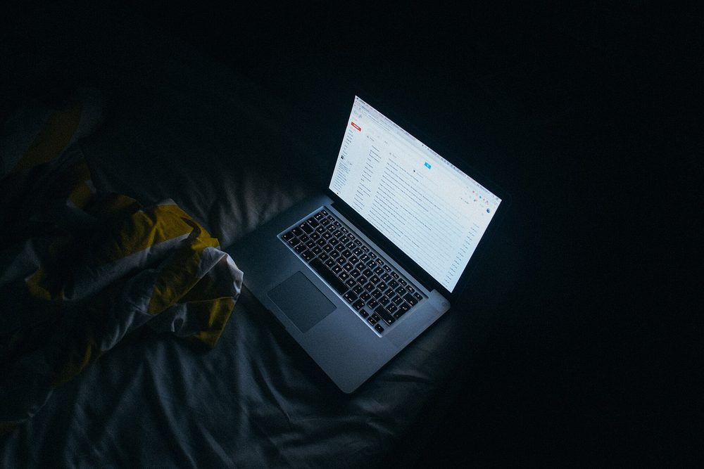 Un portátil abierto brillando sobre un escritorio en una habitación a oscuras