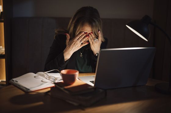 Una persona frotándose los ojos frente a un portátil de madrugada