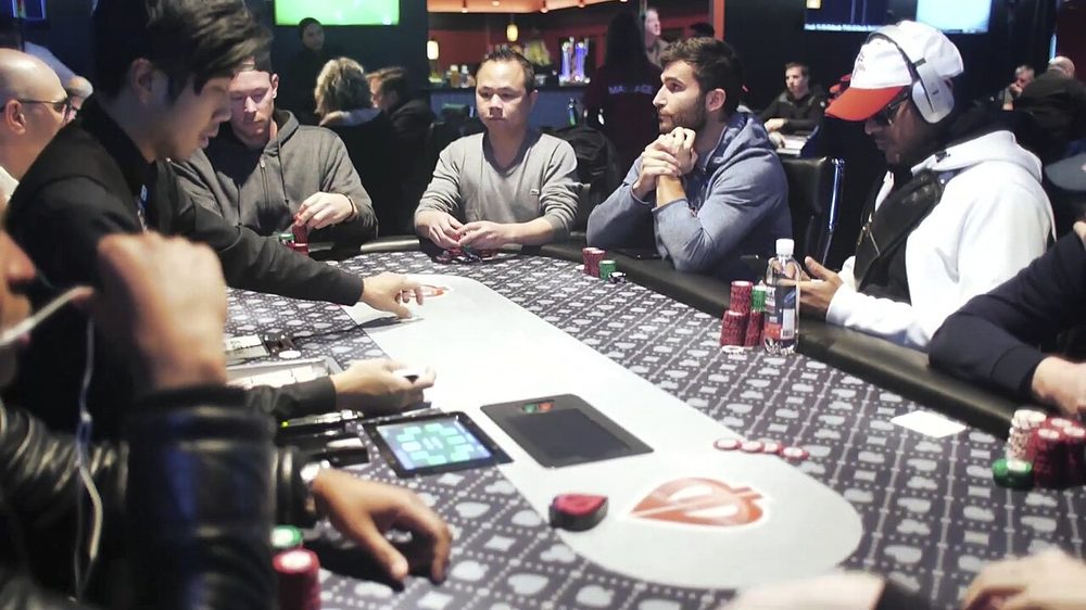 Jugadores de poker observándose entre sí al otro lado de la mesa durante una mano