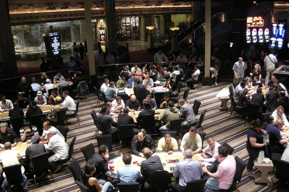 Decenas de mesas de poker ocupadas llenando la sala de cartas de un casino