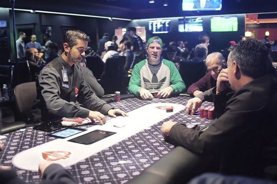 Jugadores y un crupier en una mesa de poker en vivo en una sala de cartas