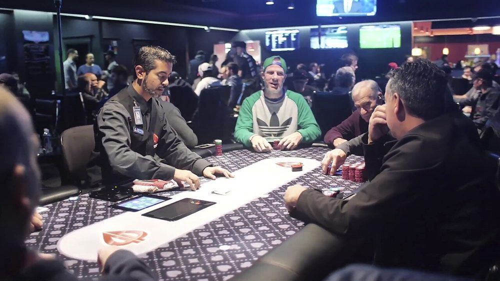 Jugadores y un crupier en una mesa de poker en vivo en una sala de cartas