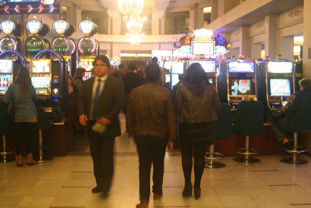 Jugadores caminando entre filas de máquinas en la sala de un casino chileno
