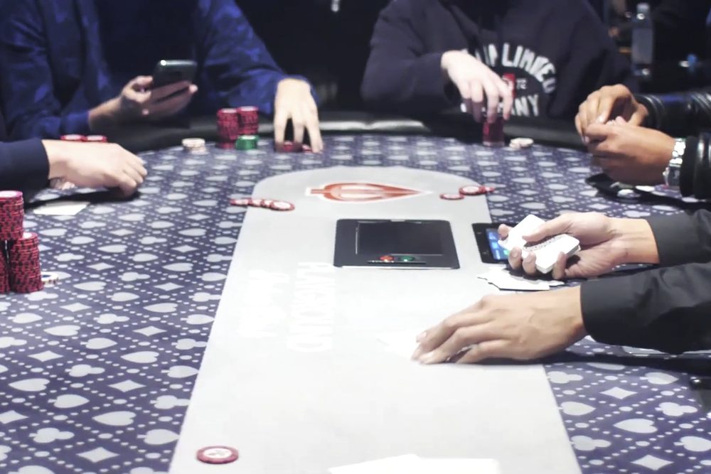 Vista cenital de las manos de los jugadores, las cartas y las fichas sobre una mesa de poker
